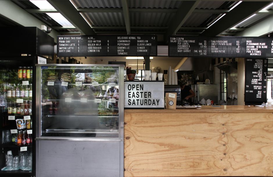 Um interior de café moderno com quadros de menus, uma vitrine e um balcão de madeira.